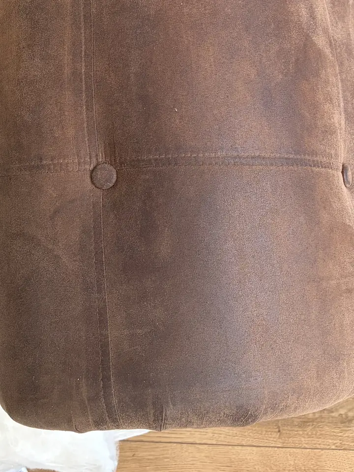 Faux suede sofa arm before cleaning, with a dark greasy patch along the top